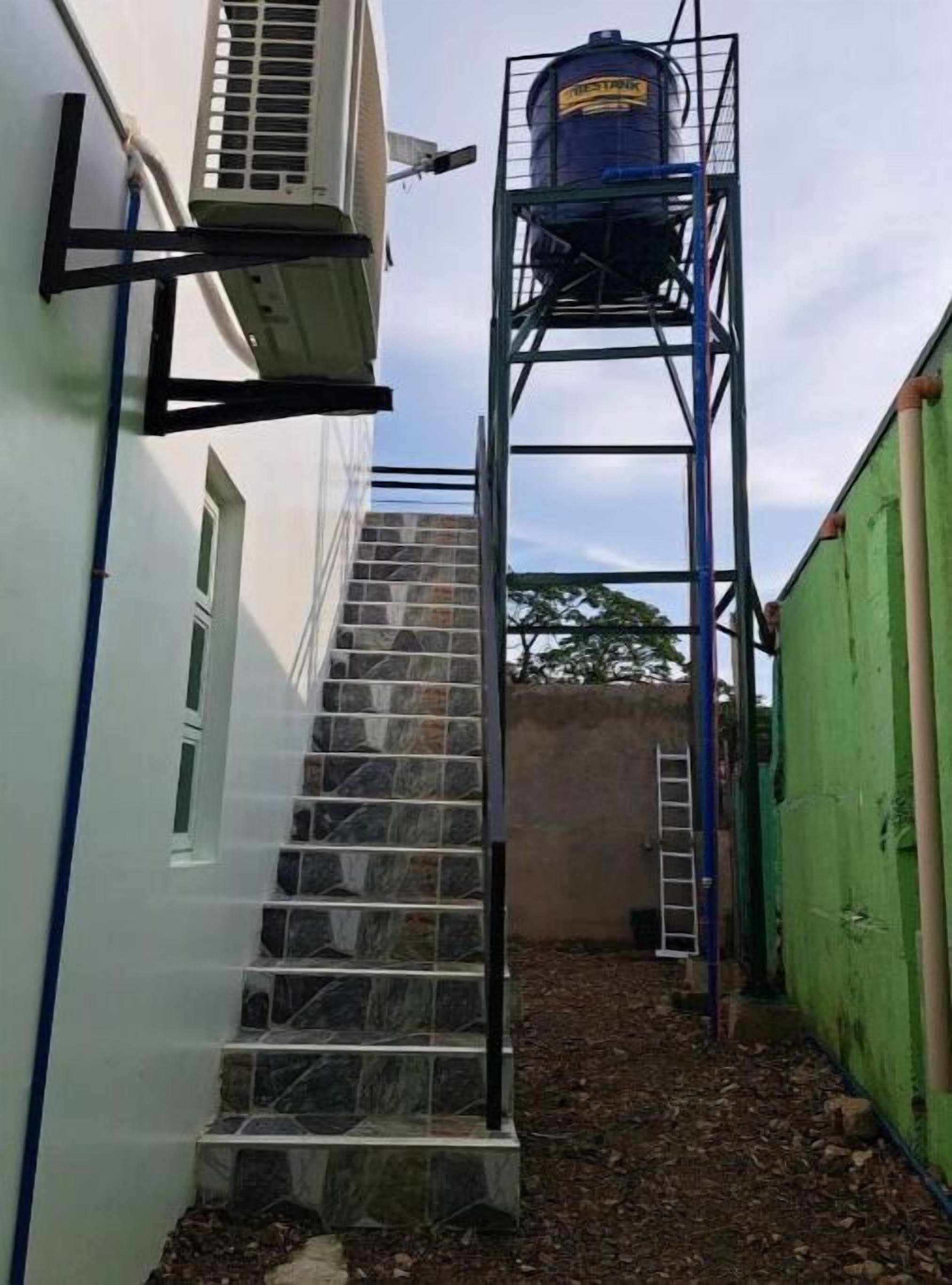 Unes escales estretes que condueixen a un dipòsit d'aigua sobre una estructura metàl·lica.