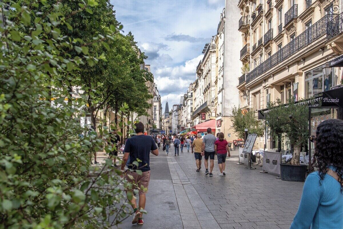 Un carrer per a vianants arbrat i flanquejat d'edificis, amb un restaurant anomenat "Pizzaia".