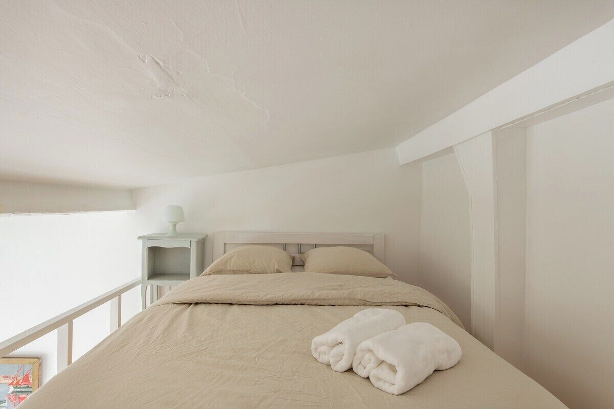 A neatly made bed with two pillows and a folded towel on a white bedspread.