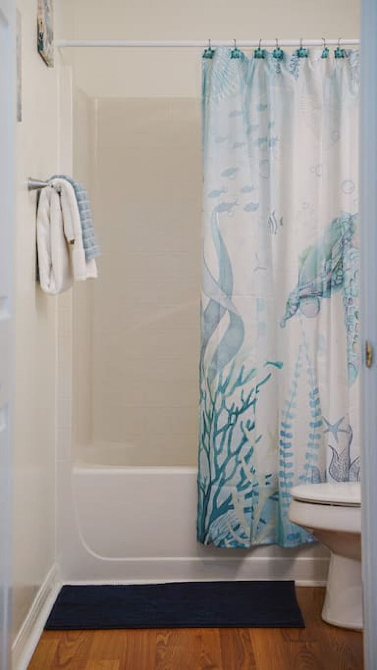 Et badeværelse med bruser, toilet og håndklædestang.