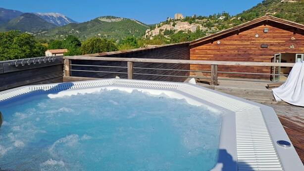 A wooden cabin with a hot tub on a deck, overlooking a mountainous landscape. - Logement 2 Chambres, Entièrement Rénové, Dans Résidence Avec Piscine (Montbrun-les-Bains)