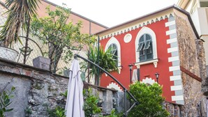 Un edificio rojo con ventanas de arco y un muro de piedra.