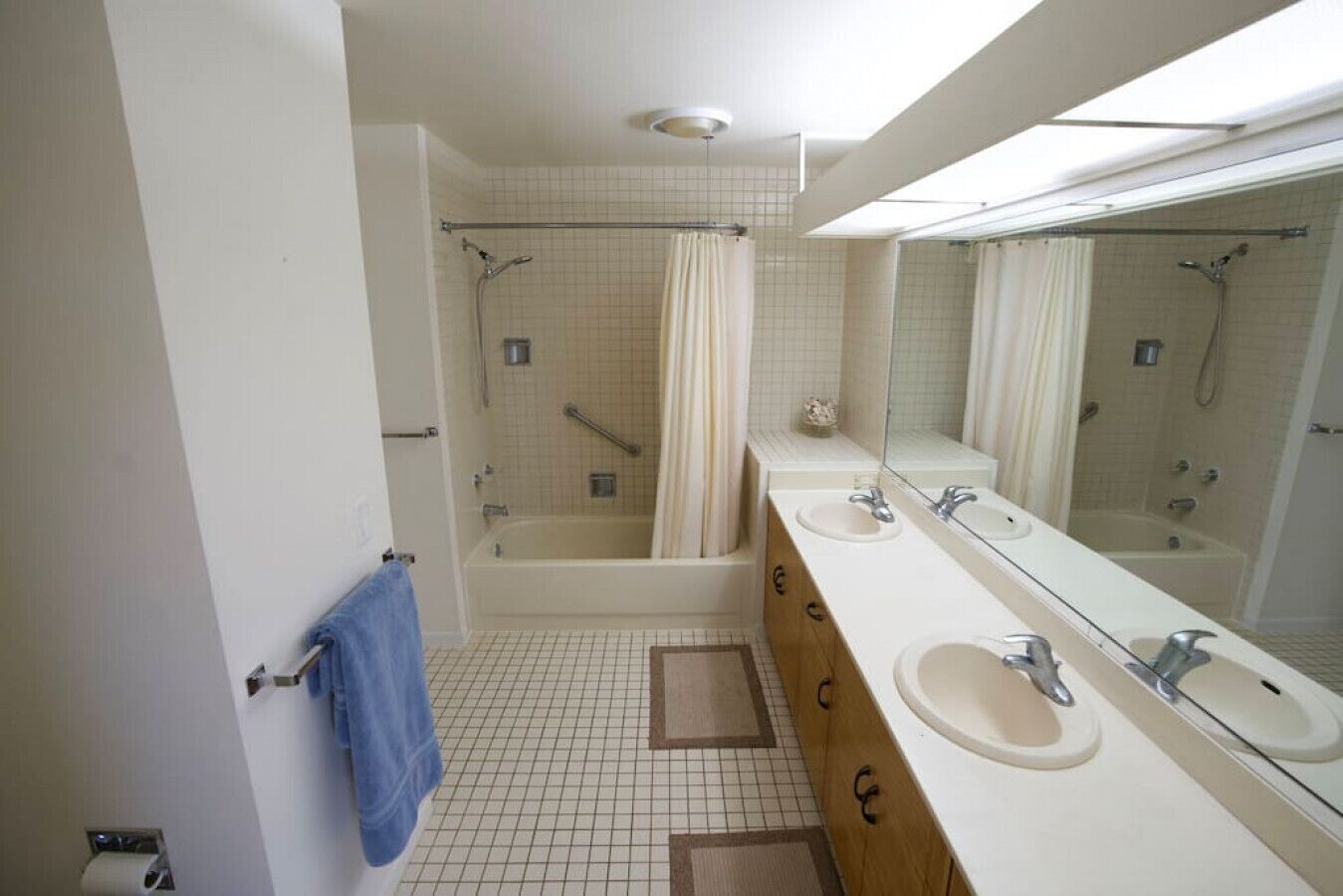 Un baño con bañera, dos lavamanos, un espejo grande y zona de ducha.