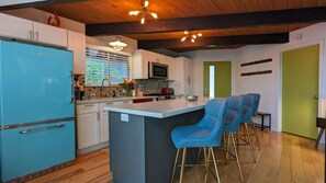 A kitchen with a blue refrigerator, white cabinets, a central island with blue bar stools, and a wooden ceiling. - Incline Village Chalet (Incline Village)