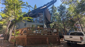 A cabin with a deck, surrounded by trees, and a white pickup truck parked nearby. - Incline Village Chalet (Incline Village)
