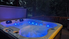 A hot tub with blue lighting, surrounded by a wooden deck and trees. - Incline Village Chalet (Incline Village)