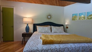 A bedroom with a bed, bedside lamps, a decorative wall piece, and a door. - Incline Village Chalet (Incline Village)