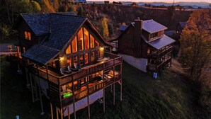 A wooden cabin with a balcony and a second-story deck, surrounded by a forested hillside. - Steps from Hatley Pointe - Short drive to downtown Asheville! (Mars Hill)