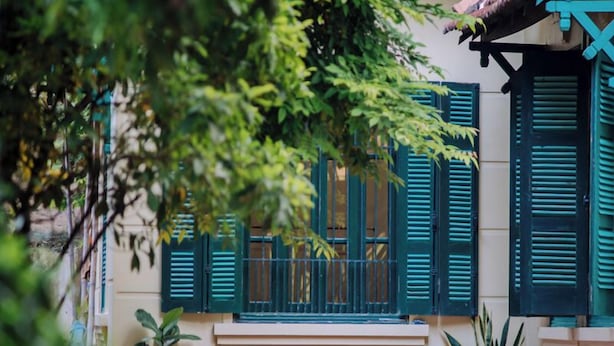 Ein Gebäude mit grünen Fensterläden und Pflanzen im Vorbereich.