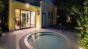 Ein modernes Haus mit Swimmingpool, Essbereich und gut beleuchteter Fassade.