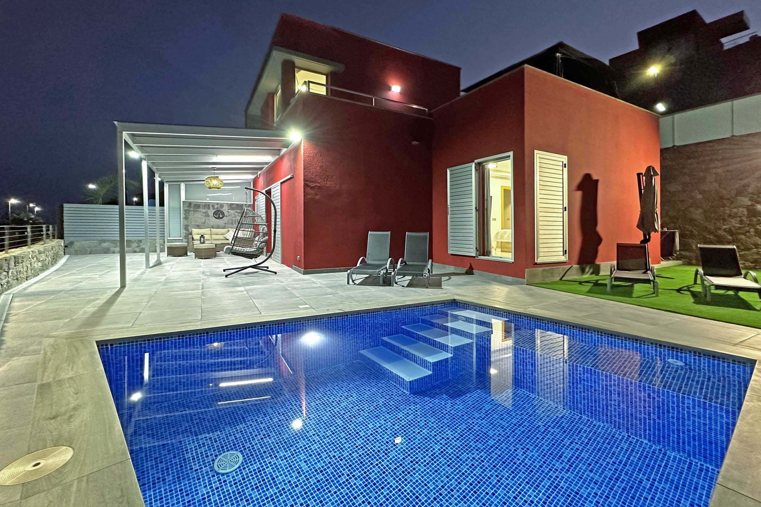 A modern outdoor swimming pool with a red building in the background.
