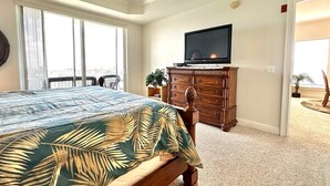 Ein Schlafzimmer mit Bett, Kommode, Fernseher und Balkon.