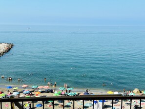 A beach with people swimming and sunbathing, umbrellas, and a rocky breakwater. - BluMare ArtHouse (Salerno)