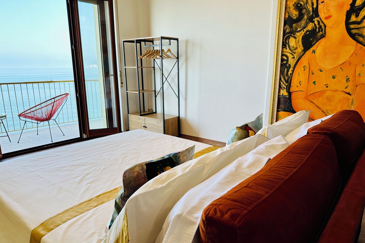 Une chambre d’hôtel avec un lit, une chaise rouge, une armoire et un tableau.