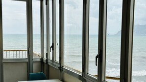 A room with a view of the ocean through large windows, a table, and two chairs. - BluMare ArtHouse (Salerno)