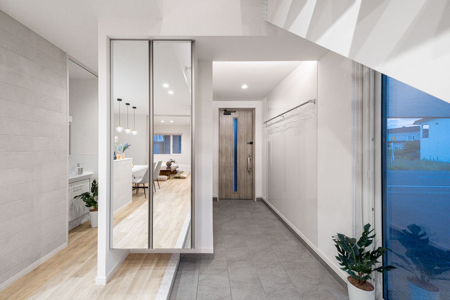 A modern interior with a kitchen, dining area, and a hallway leading to a bedroom.