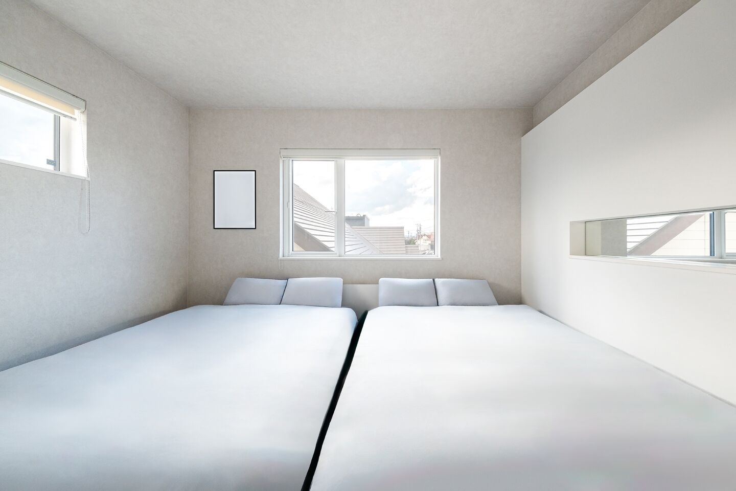 A modern, minimalist bedroom with two beds, a large window with a view of a building, and a framed picture on the wall.