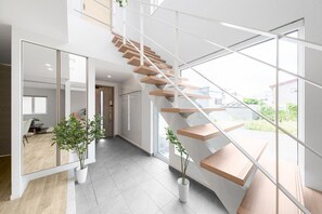 A modern interior with a wooden staircase, large windows, and potted plants. - THE PRESTIGE (Asahikawa)