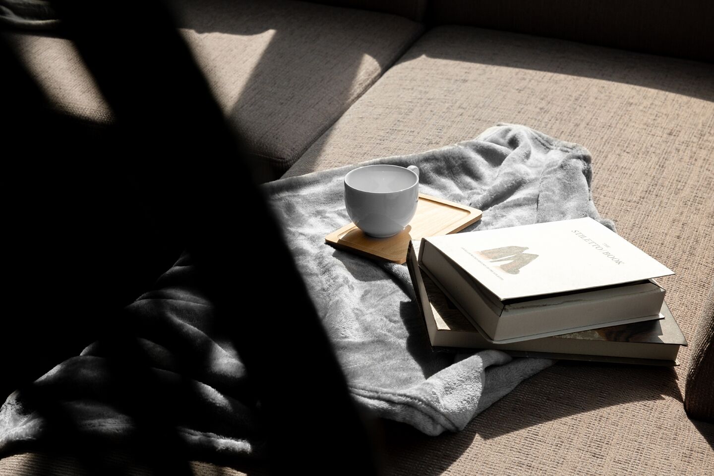 Un coin lecture confortable avec une couverture, une tasse et un livre sur un canapé.