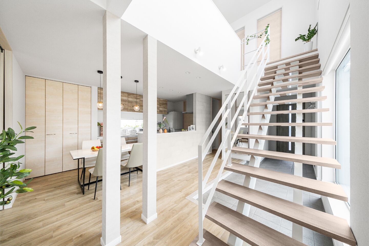 A modern interior with a staircase, wooden flooring, and a dining area.