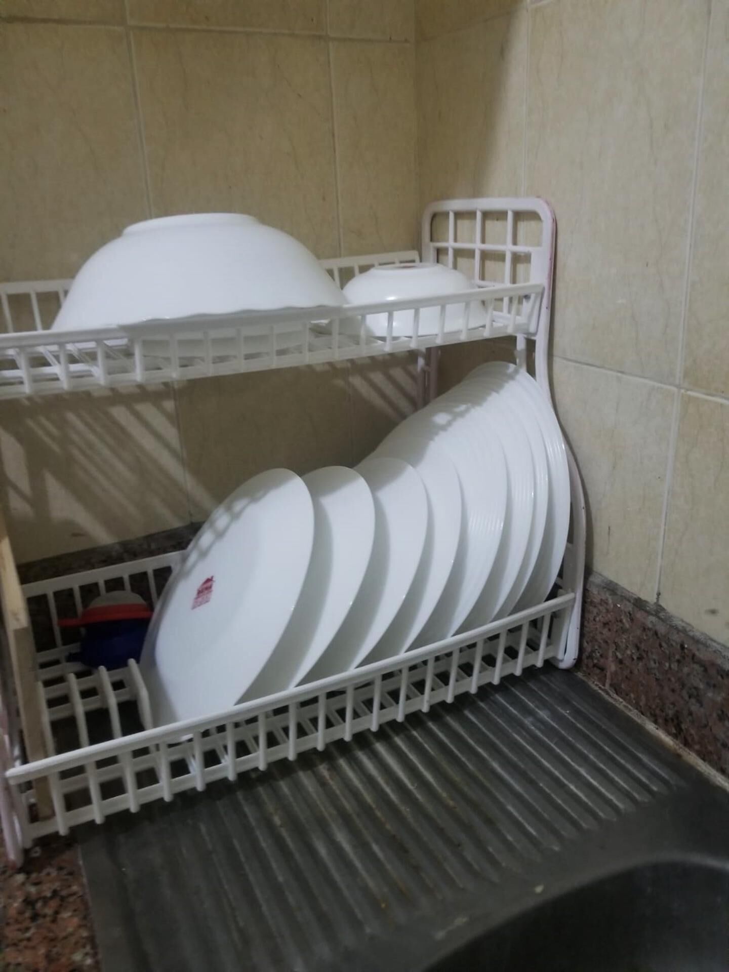 Un escorredís blanc amb nombrosos plats i tassons blancs.