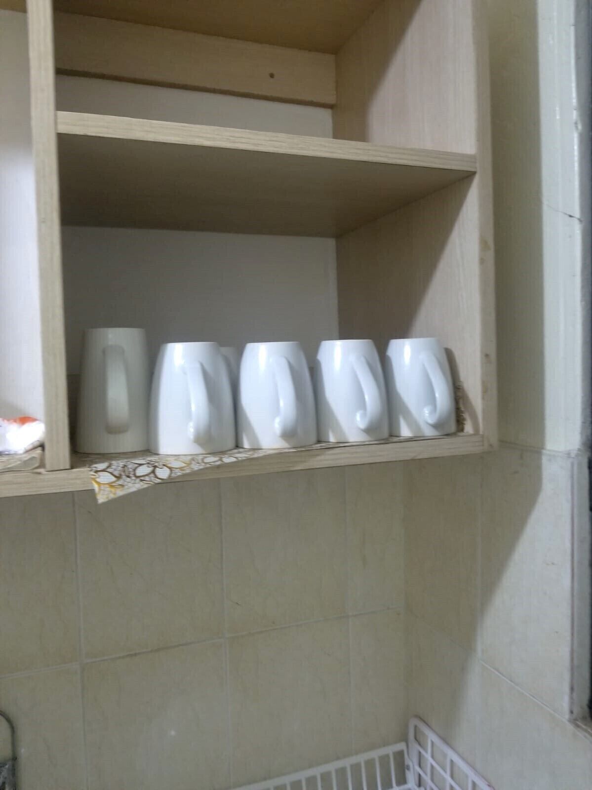Una repisa con seis tazas de cerámica blanca.