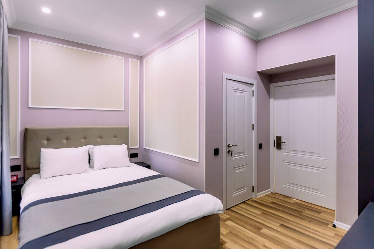 Un dormitorio con cama, dos puertas y pared de color claro.