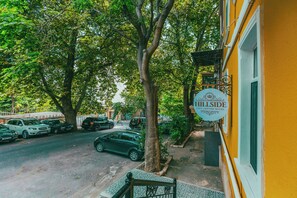 Une vue de rue avec un bâtiment jaune portant l’inscription « Hillside City Center Hotel ».