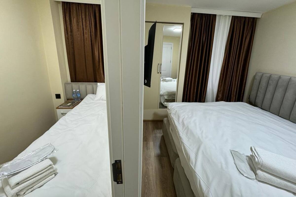 Habitación de hotel con dos camas, una mesita de noche, un espejo y una puerta.