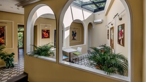 Un pasillo con arcos, tragaluces y obras de arte en las paredes.