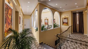 Un pasillo de hotel con suelo a cuadros, arcos en las puertas y cuadros en las paredes.