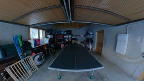 Ein Zimmer mit einem Tischtennis-Tisch, Regalen voller Gegenstände und einem Fahrrad.