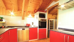 Eine Küche mit roten Schränken, Edelstahlgeräten und Holzbalken an der Decke.