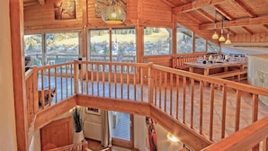 Eine Holzdiele mit Balkon, großen Fenstern und einem Essbereich.