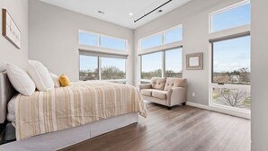 Une chambre spacieuse dotée d’un grand lit, d’un canapé et de nombreuses fenêtres donnant sur l’extérieur.