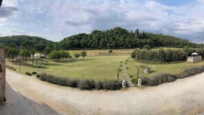 Une vue d’un espace aménagé avec un chemin de gravier, des champs couverts d’herbe et un petit bâtiment doté d’un toit.