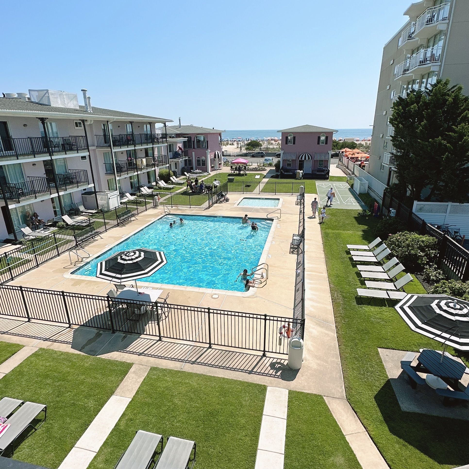 Una piscina con un deck circundante, sillas de descanso y vista al mar.