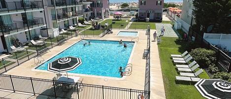 Una piscina con un deck circundante, sillas de descanso y vista al mar.