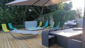 A wooden deck with outdoor furniture, including chairs and a table, and a barbecue grill.
