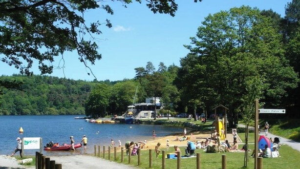 A lakeside park with a sandy beach, a playground, and a boat dock.