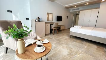 A modern hotel room with a bed, a desk, a chair, a coffee table with a plant, and a TV.
