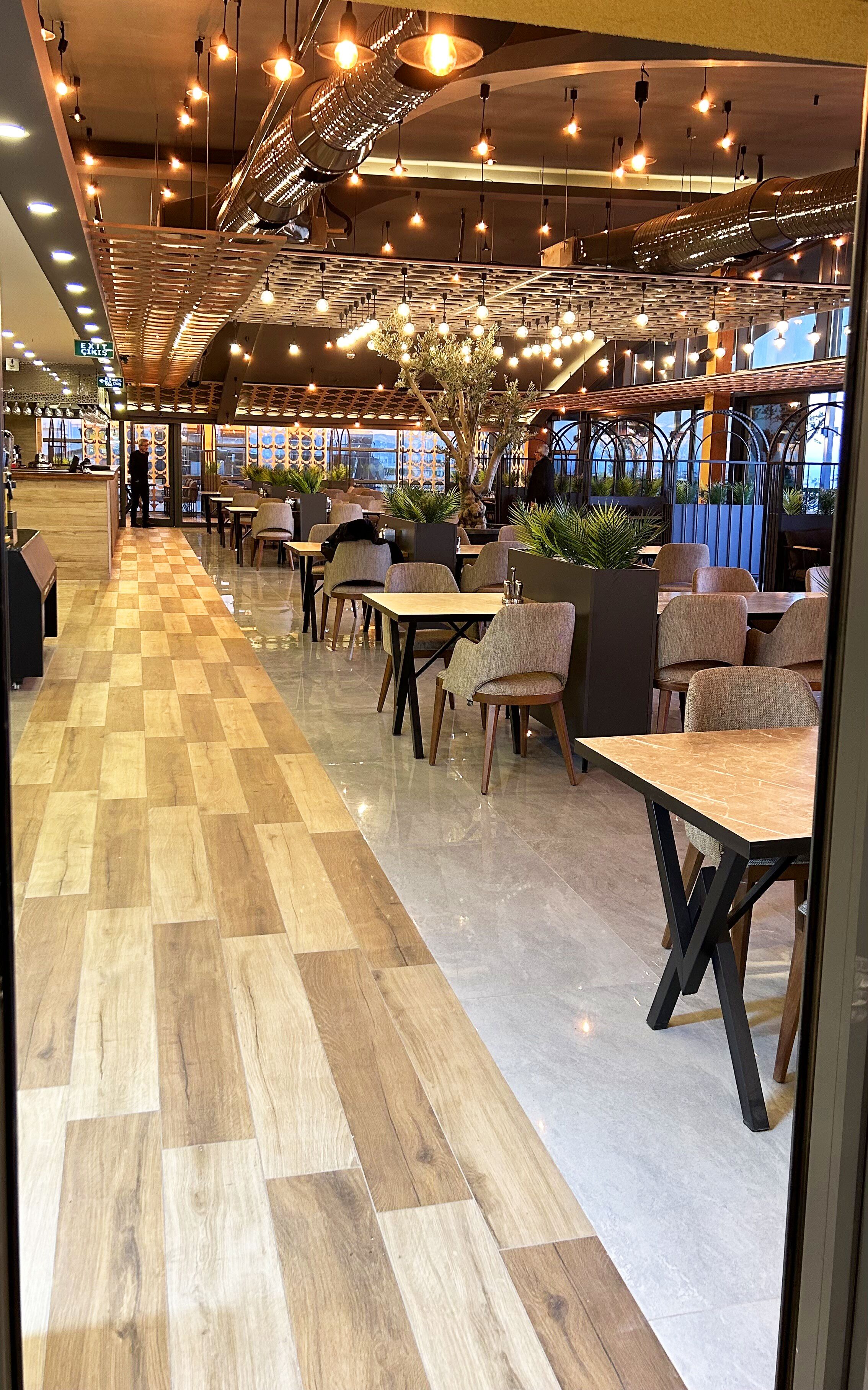 En modern restaurang med ett rutmönstrat golv, träbord och hängande taklampor.