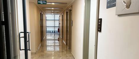 Un pasillo de hotel con un extintor, un letrero de precaución y señales direccionales.