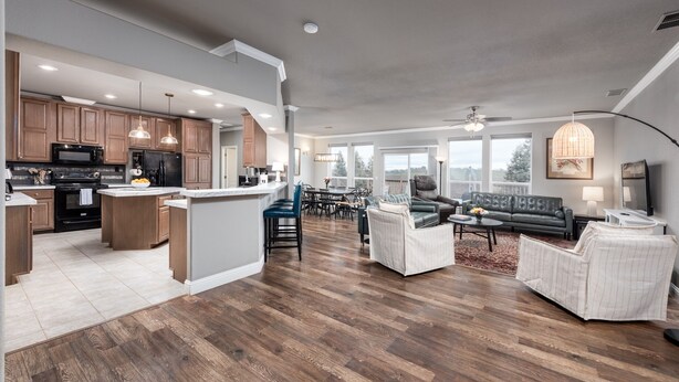 A modern kitchen with wooden cabinets, a central island, and a dining area with a sofa and coffee table. - Vineyard Vista Retreat | Close to Wineries, Lakes, & More! Sleeps 6, Hot Tub (Clements)
