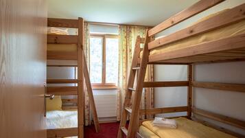Une chambre avec un lit superposé, une échelle en bois, une fenêtre avec des rideaux et une porte.