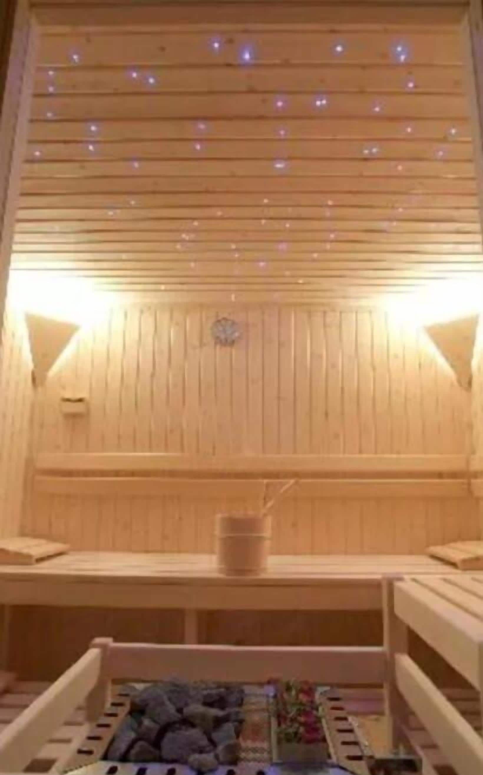 A wooden sauna with benches and a central heating element.