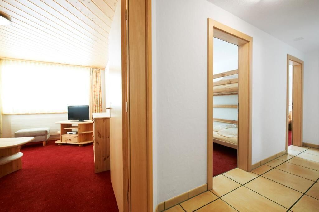 A room with a bunk bed, a television, a small table, and a red carpet.