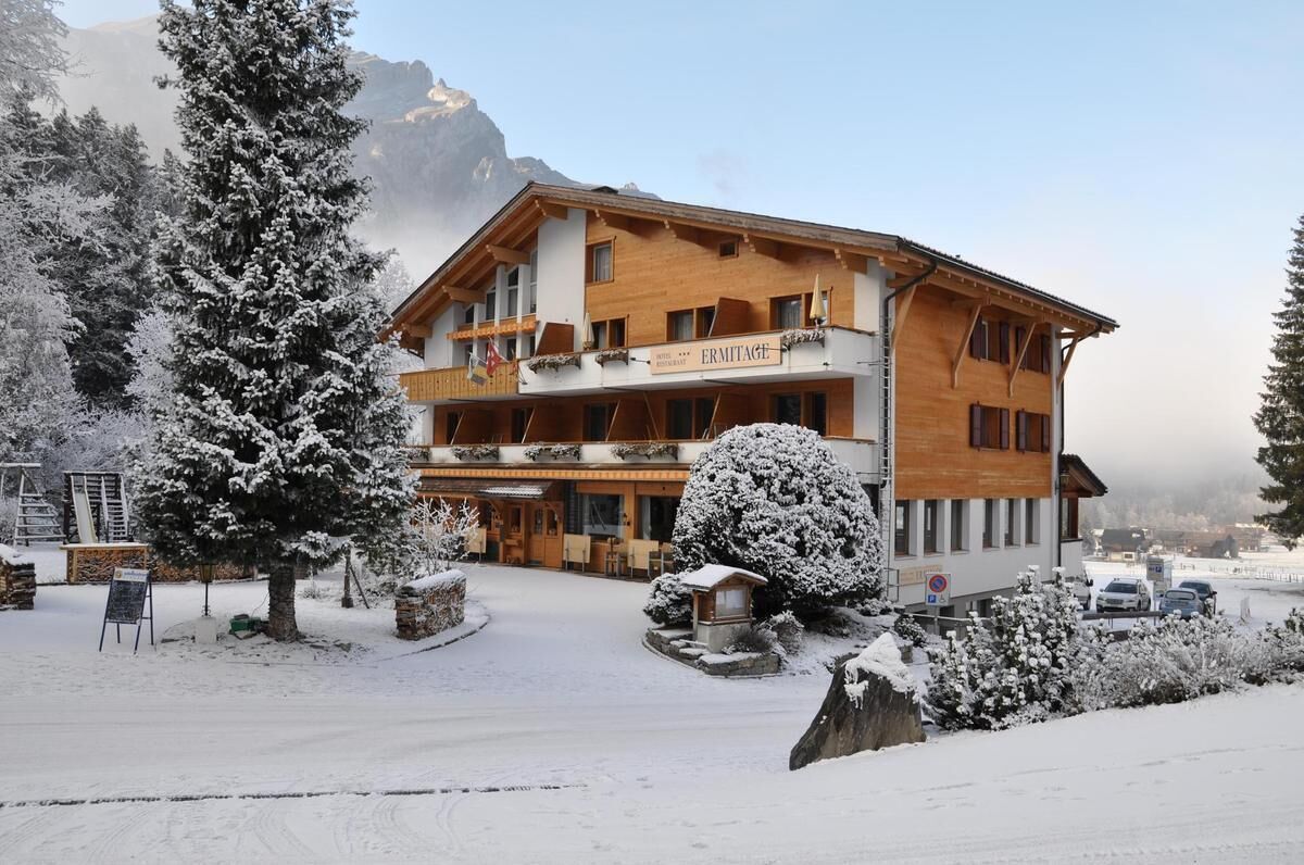 Un hôtel à plusieurs étages, doté d’une façade en bois, de balcons et d’une enseigne indiquant le nom « ERMITAGE ».