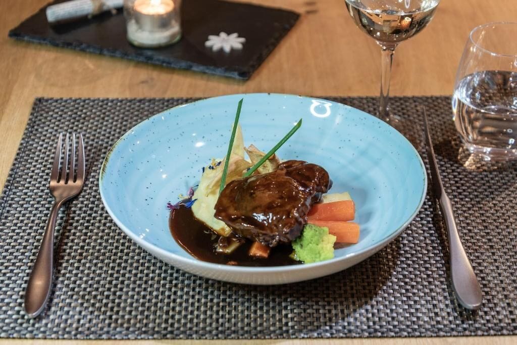 Un plato de comida con tenedor y cuchillo sobre un camino de mesa tejido.