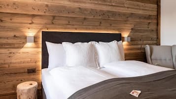 Une chambre avec un mur recouvert de panneaux de bois, un lit avec une literie blanche, une table de chevet et une chaise.